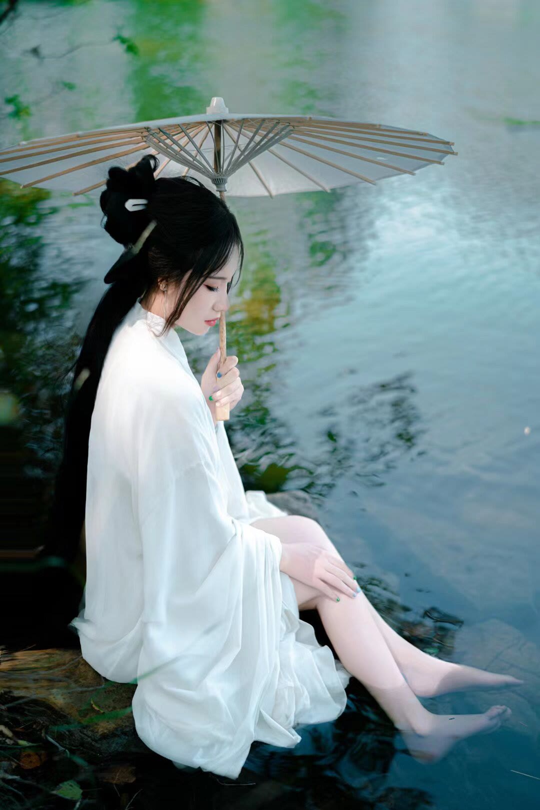 穿着汉服,光着个脚丫子,撑着把纸伞,来到这湖水边