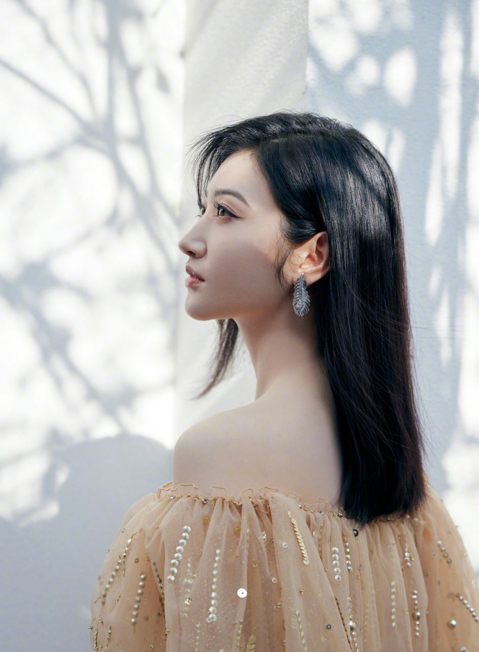 "78景甜身穿金色露肩长裙,长发披肩,侧身看向别处,优雅自如,显得