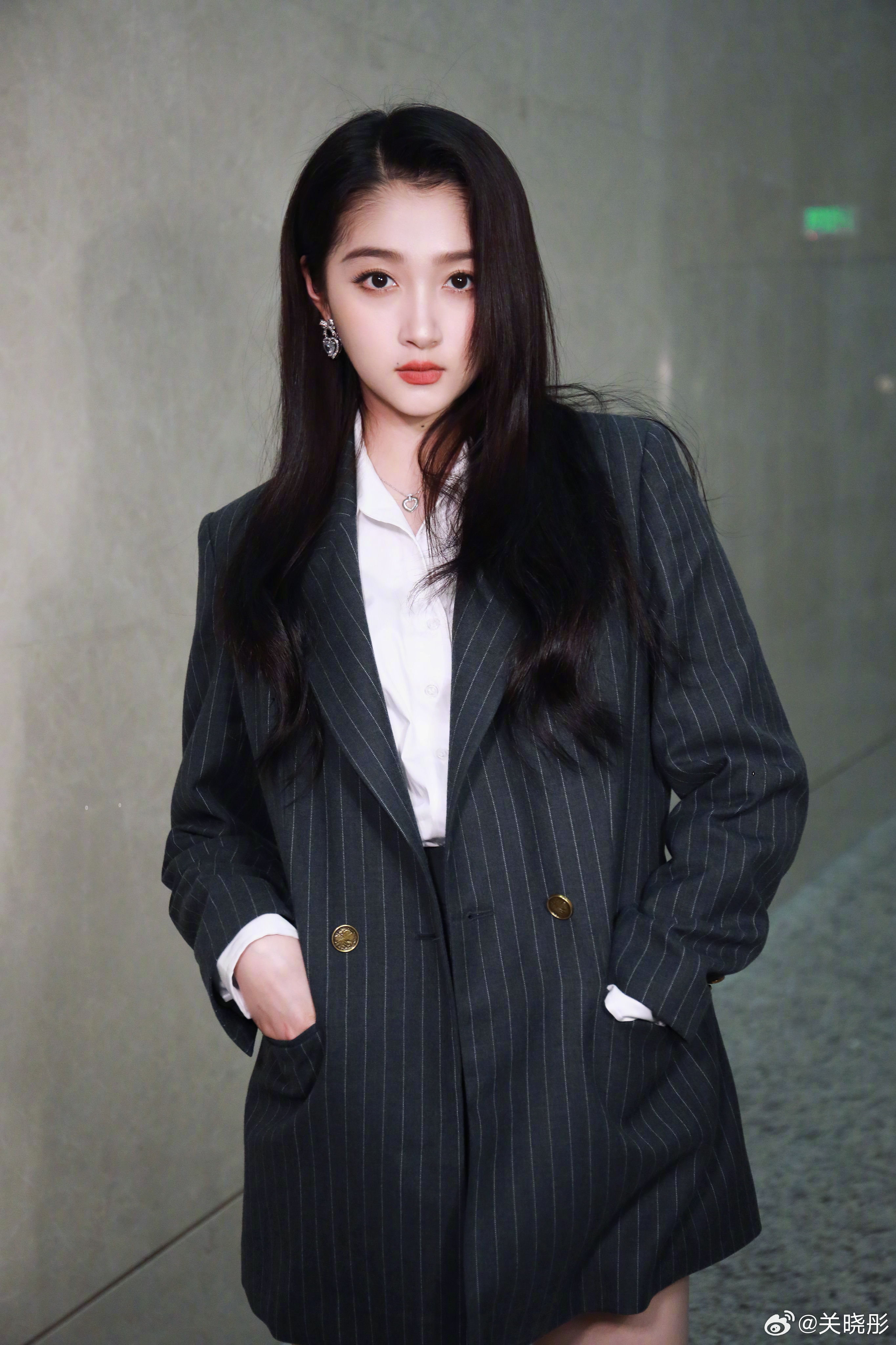 在黑白条纹的西装外套与白色衬衫的搭配下,关晓彤站在灰色背景前,手插