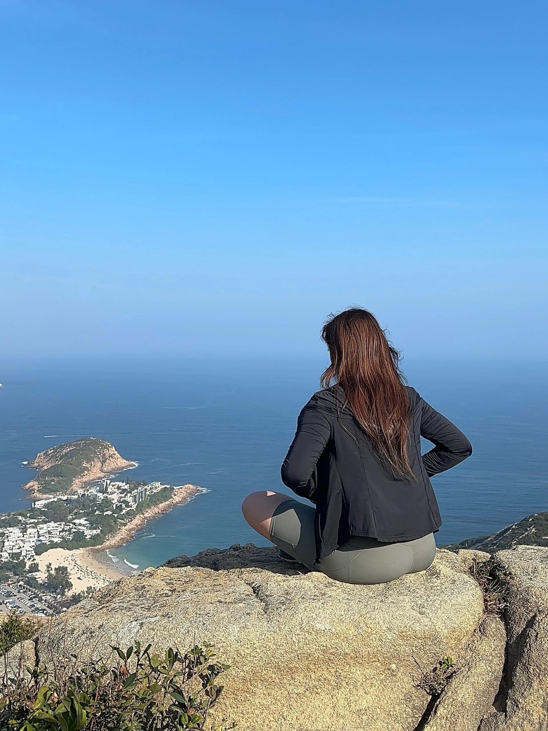 有着棕色大波浪头发,身穿休闲瑜伽服的美女,在高山和大海构成的环境