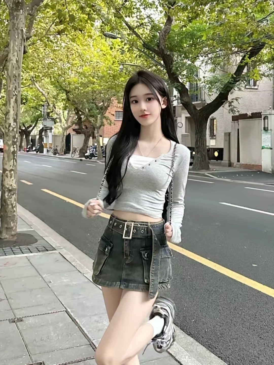 在炎热的夏天,一位美丽的女孩穿着时尚的牛仔短裙和灰色上衣,站在马路