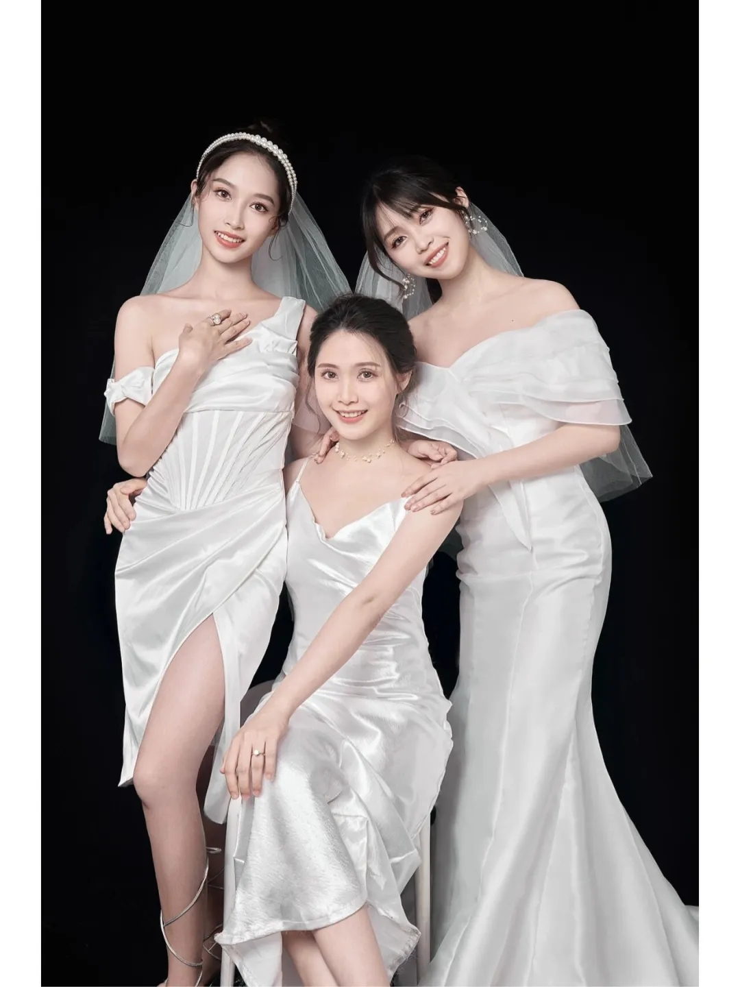 三姐妹身穿白色礼服,笑容甜美,在黑色背景下显得更加亮眼
