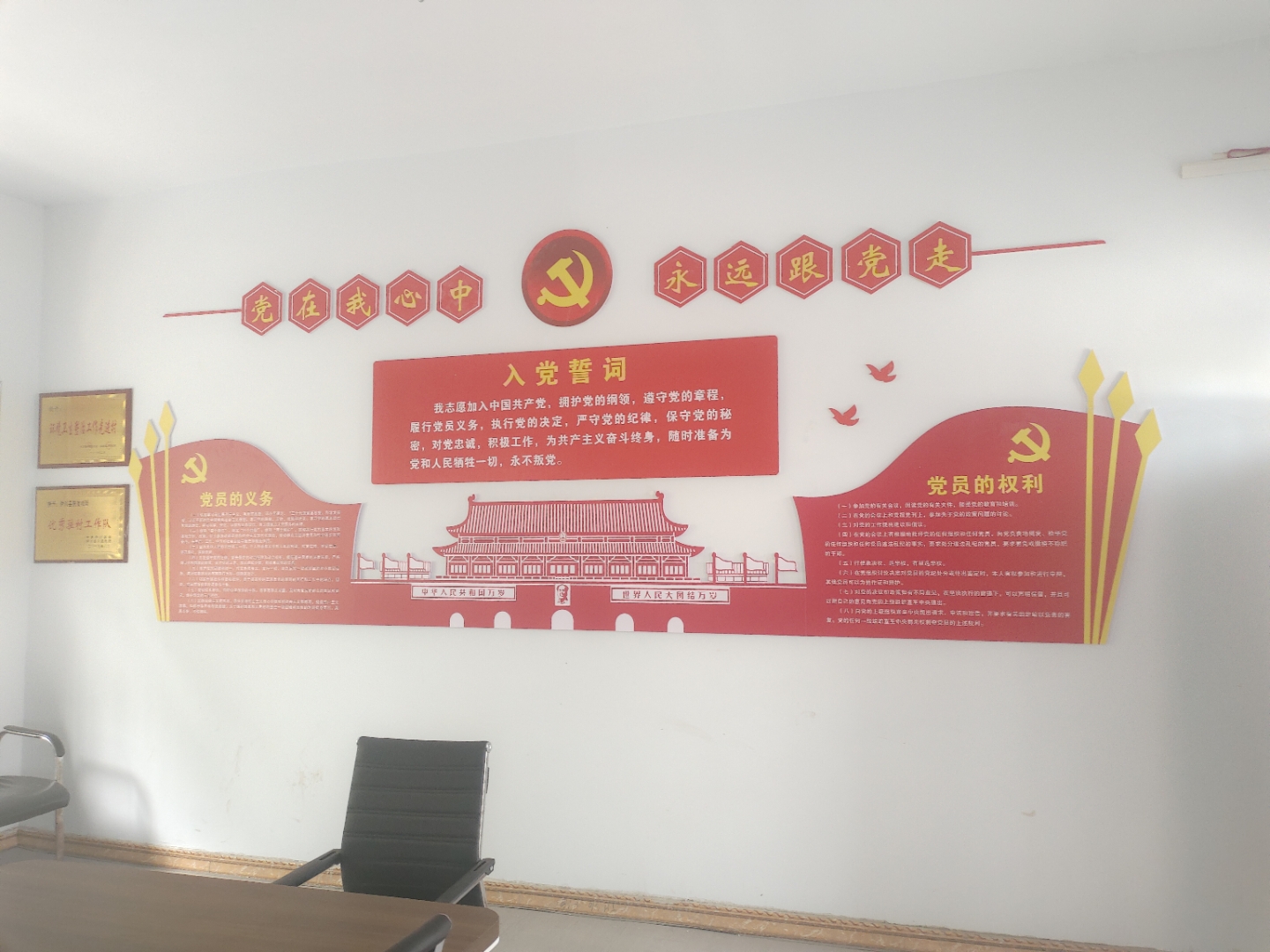 会议室内,长方形木质桌上黄花红旗相映,八椅环绕,后方墙上电视播放