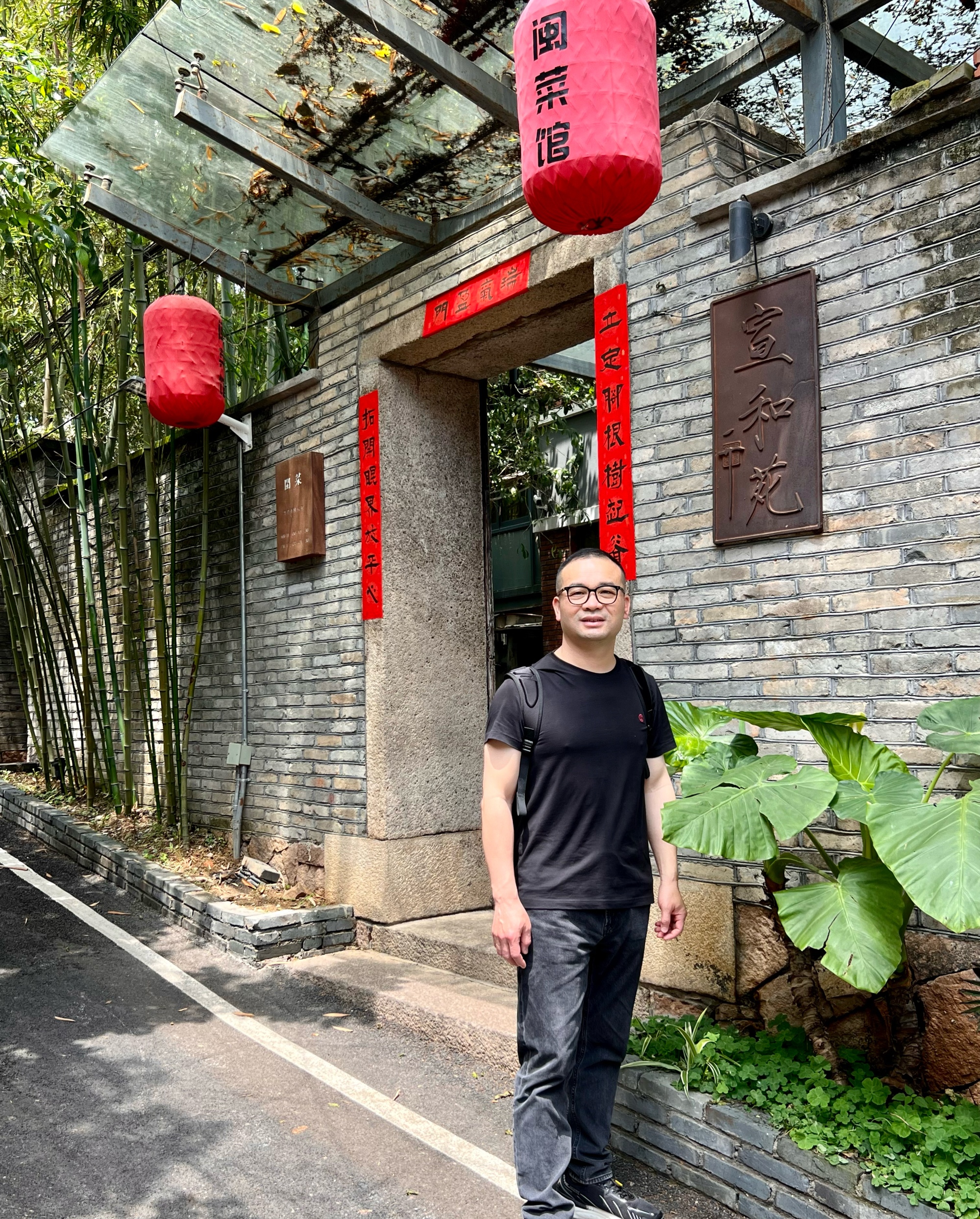 这位温文尔雅老板微笑迎客,他背后的灰砖古建,红色灯