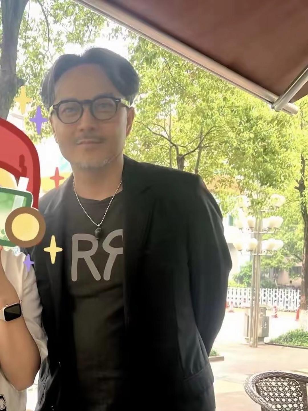 他身着黑色休闲西装戴着黑框墨镜中分发型整齐利落周身透着贵气