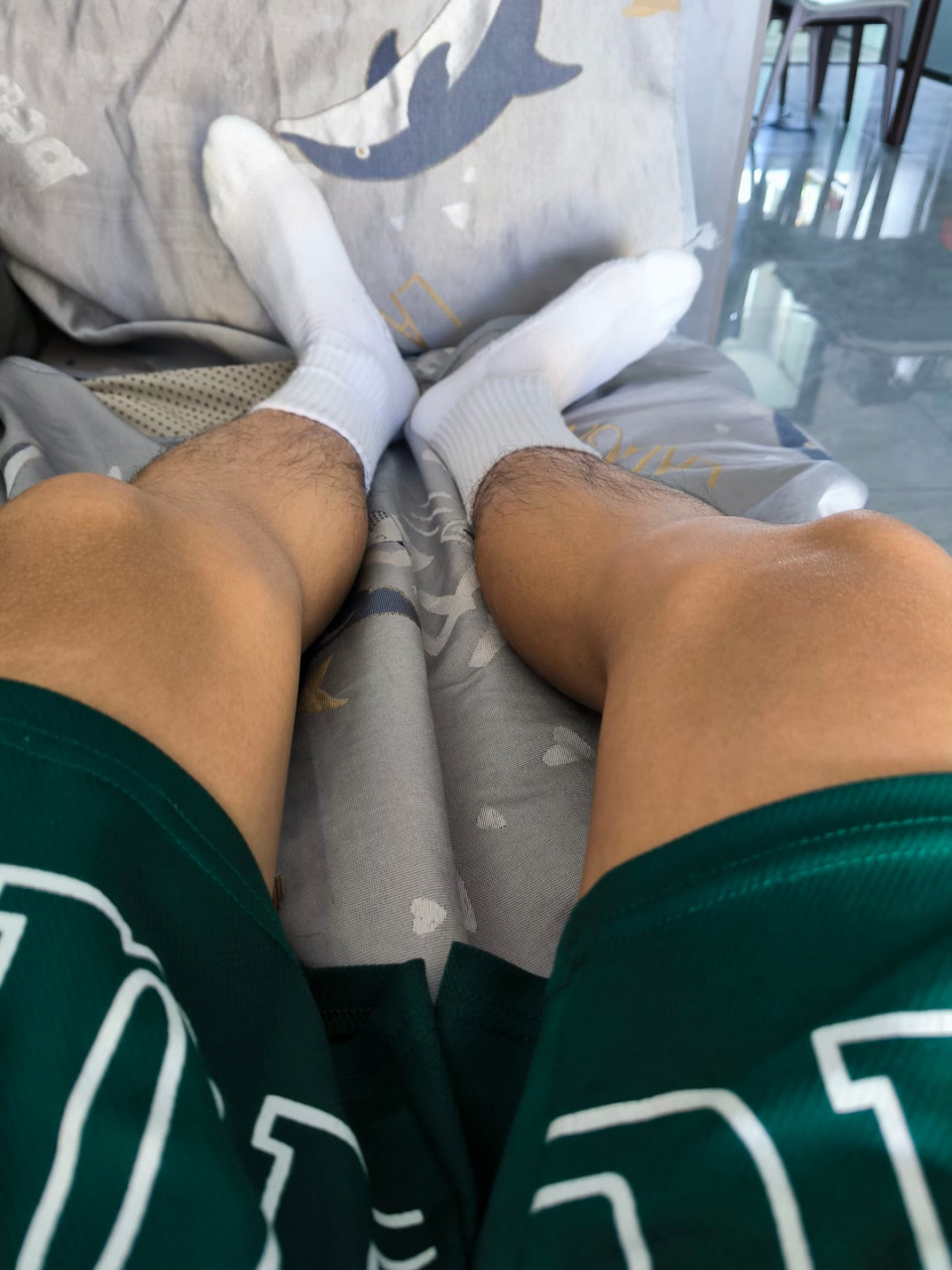 "闲适午后,静坐灰色沙发之上,双脚轻搭扶手,白袜与蓝白相间的设计相映