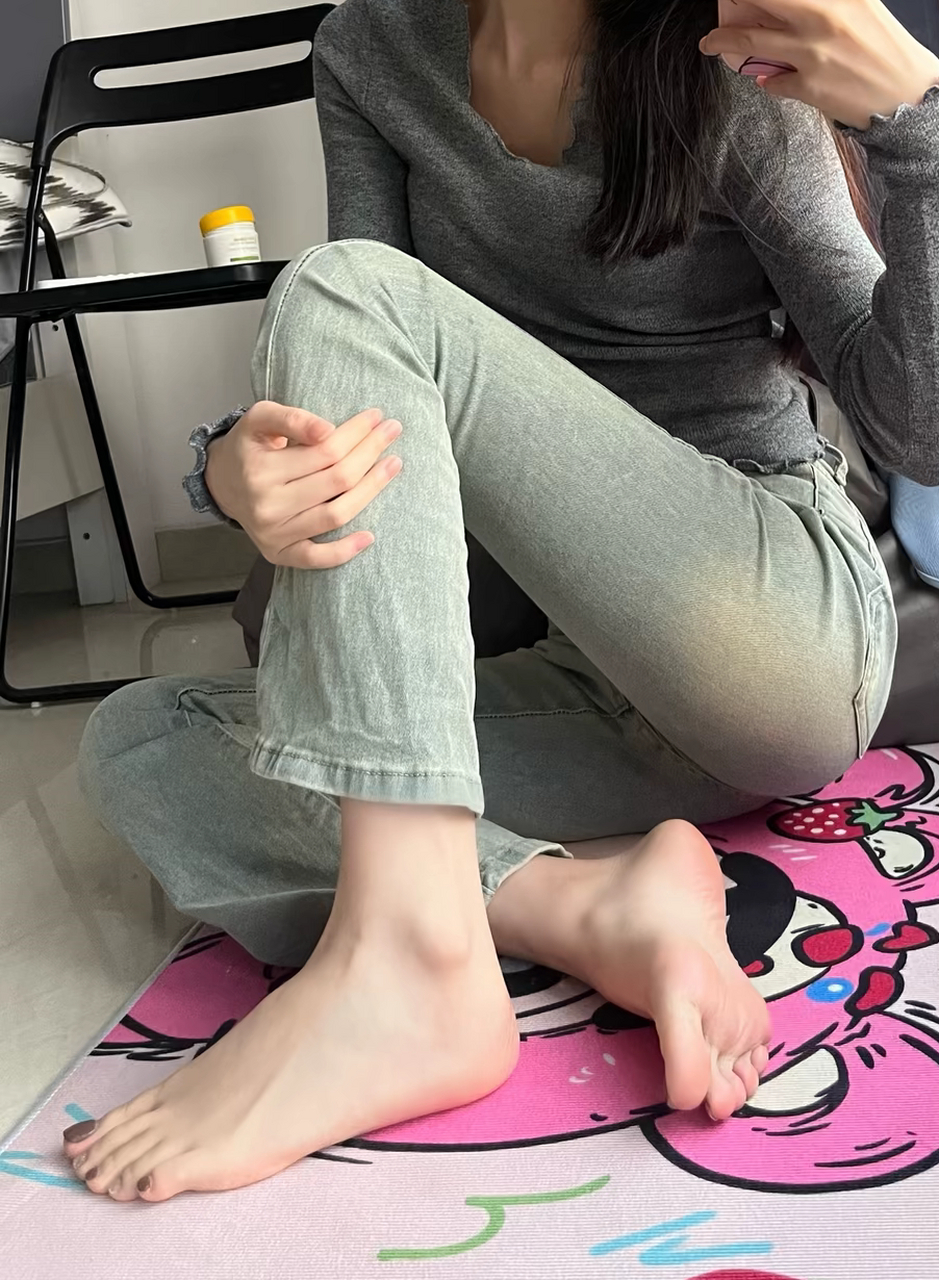 "赤脚坐在地毯上,牛仔裤与运动鞋的搭配透出一丝随性与舒适.