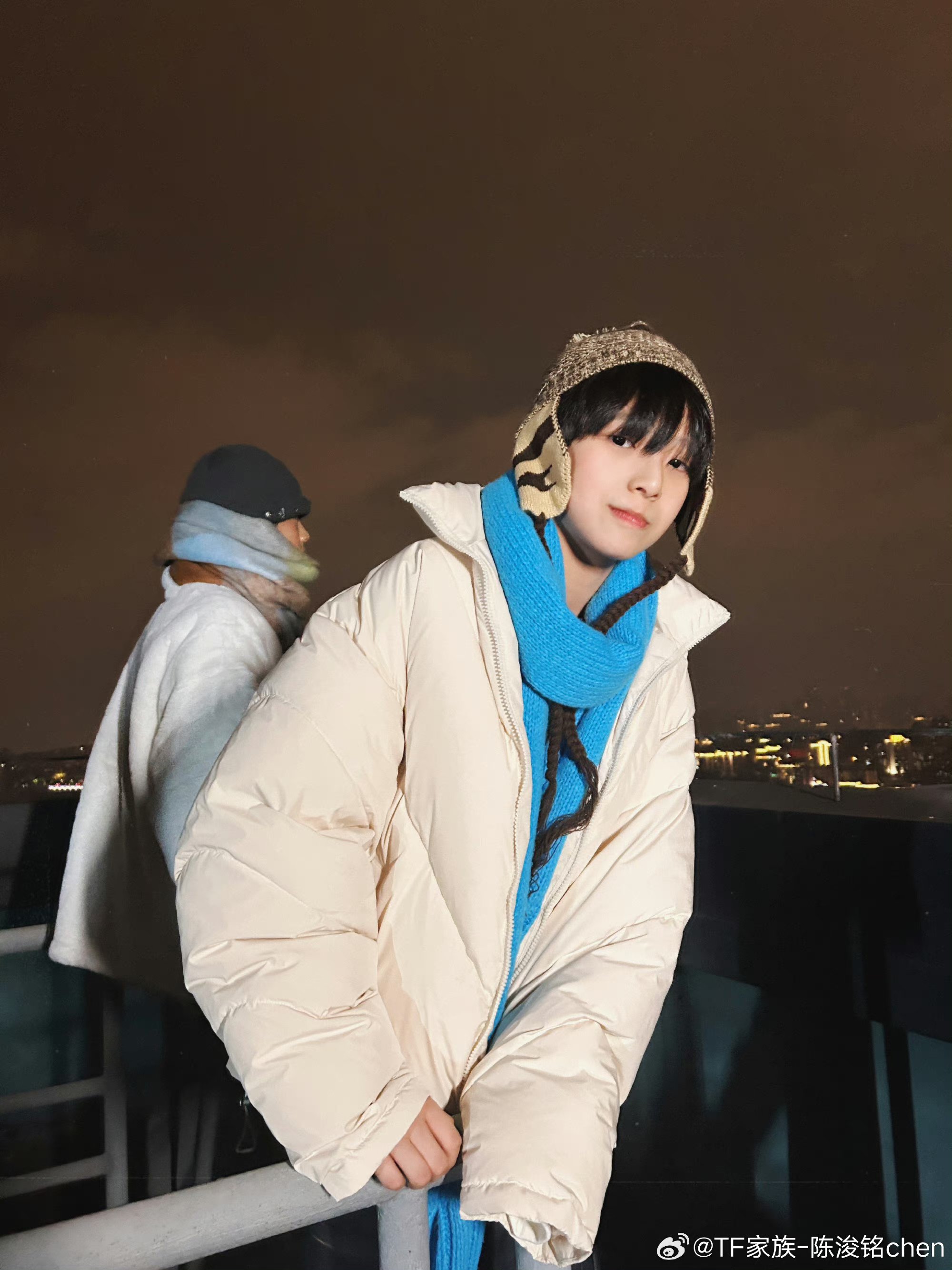 他身着白羽绒服,蓝围巾轻绕颈间,条纹毛衣增添了几分活泼