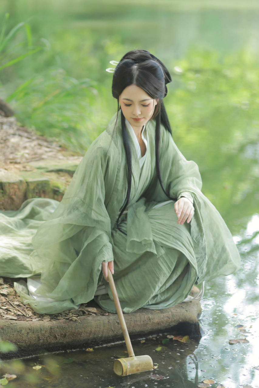 古风美女,身着淡绿的丝质长裙,优雅地坐在湖边,眉眼含笑,清雅温婉.