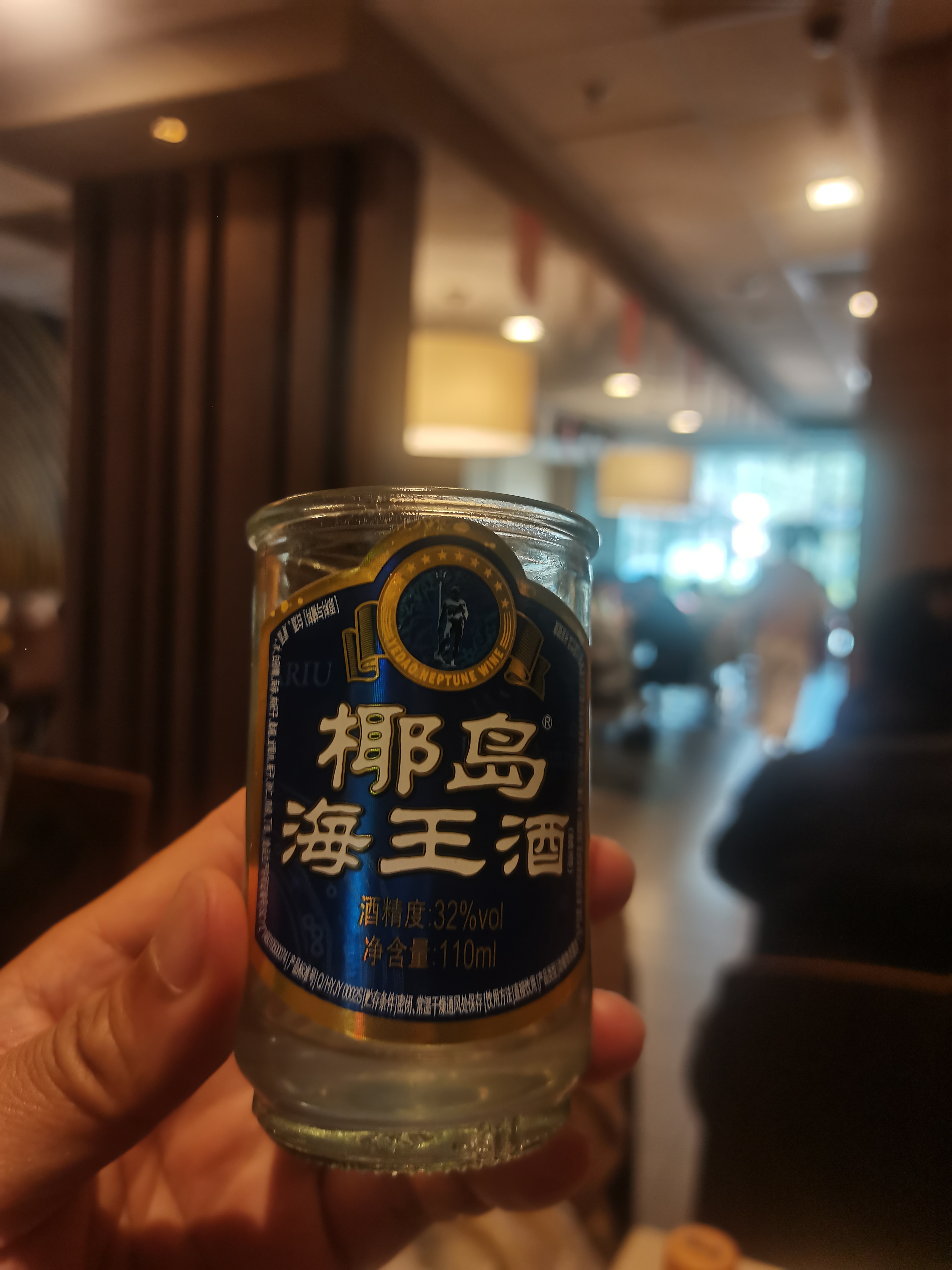 椰岛海王酒瓶身蓝金配色,正面清晰标识,32%vol,110ml,背景室内环境.