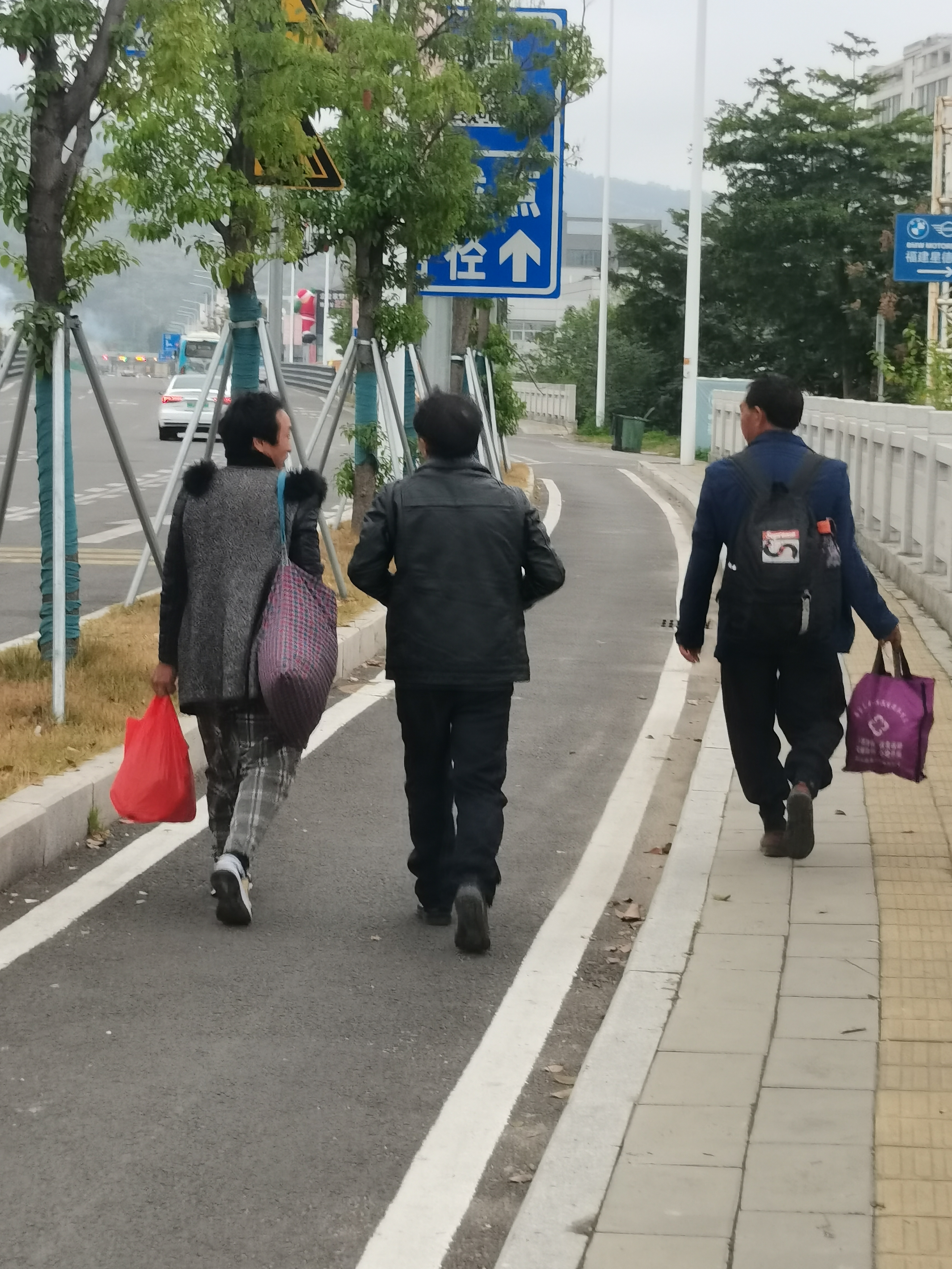 仨个行人,他们带着黑色的包,步伐坚定