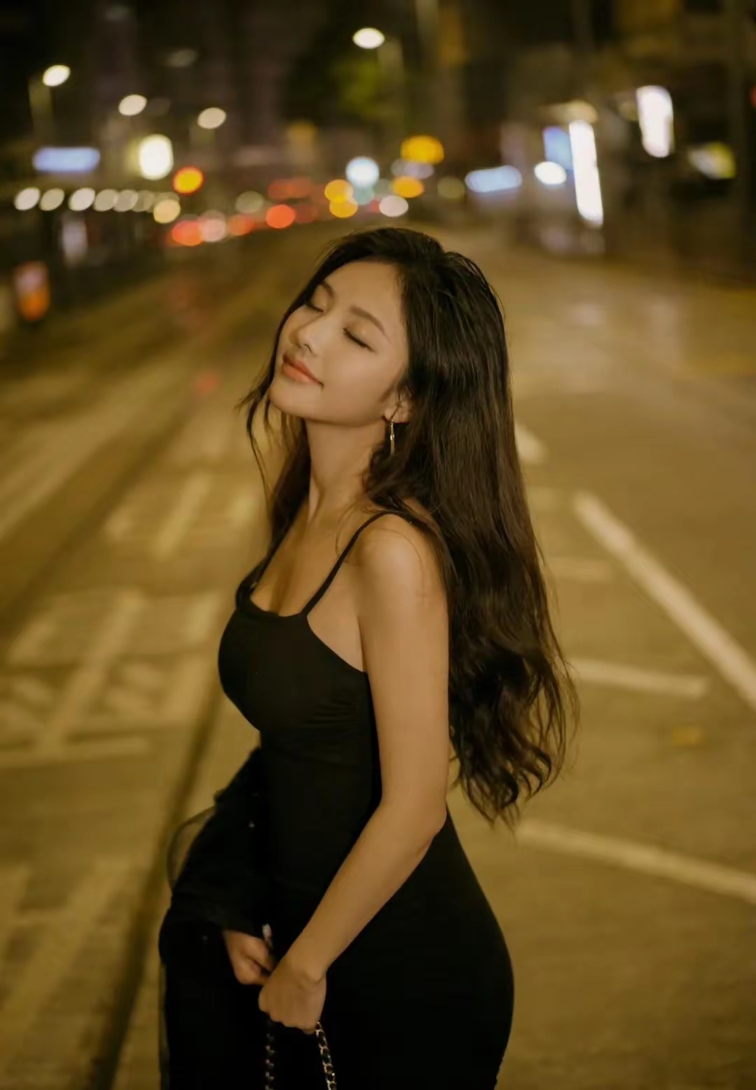 夜晚街头的迷人少女,黑色连衣裙与灯光相映成趣