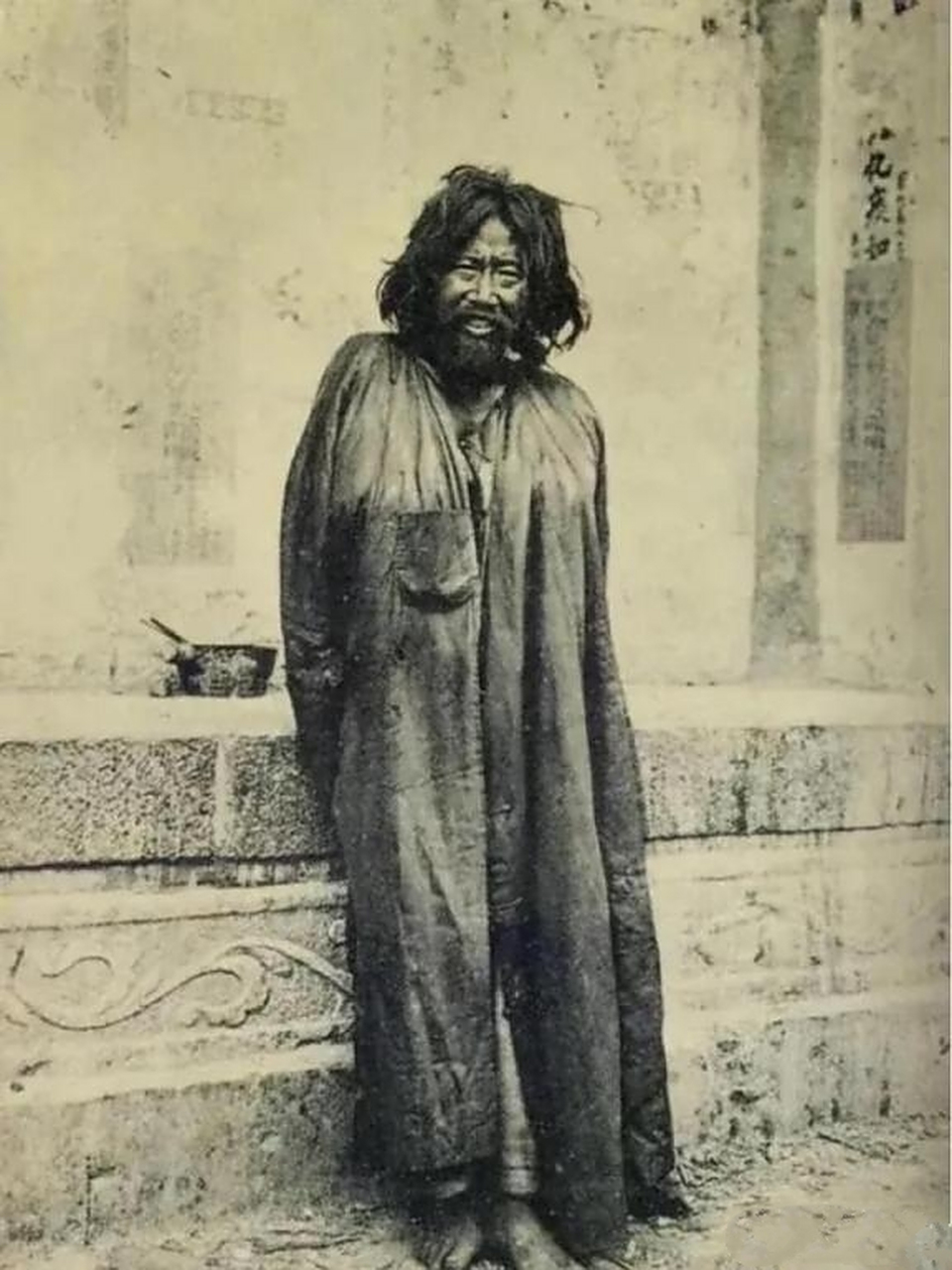 照片中这位披头散发,披着一件脏兮兮的棉袍,赤着脚打扮和乞丐一样的人