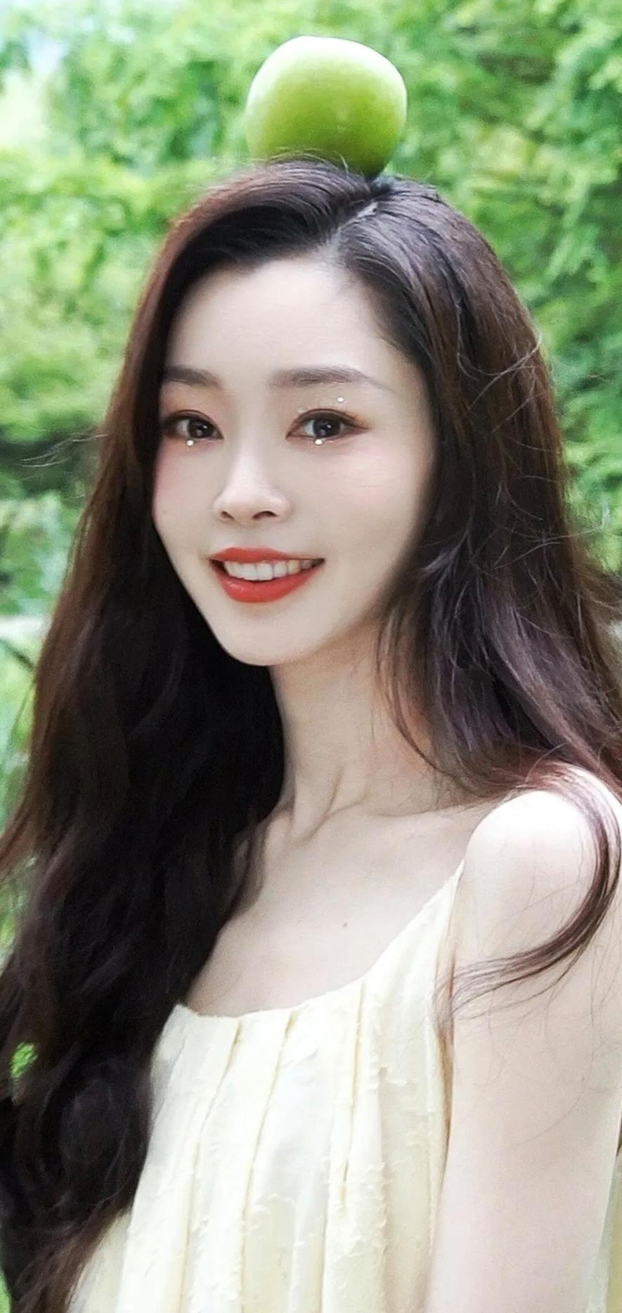 在葱郁绿意中,宋轶长发飘逸,淡黄裙衬青春容颜;闭眼浅笑或顶青苹果