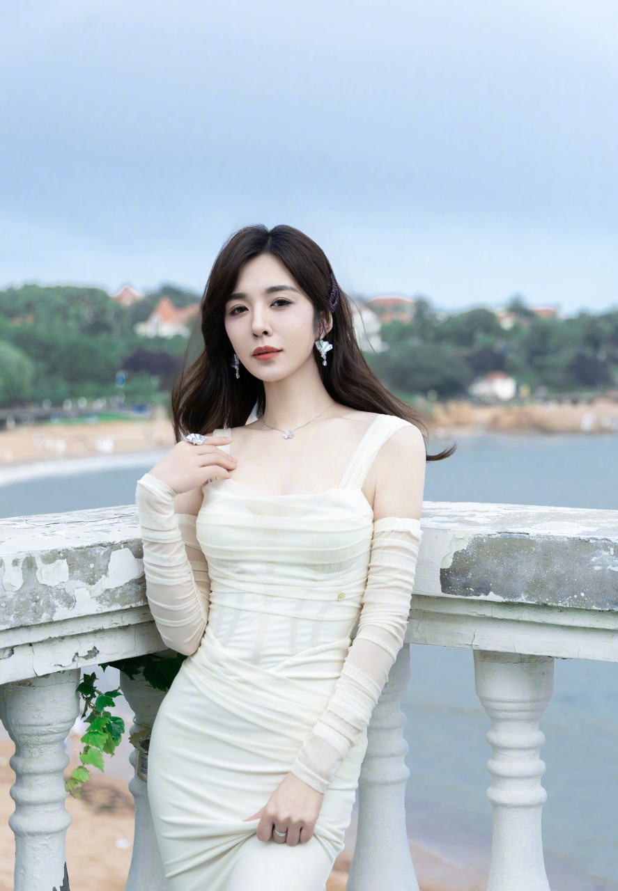 王晓晨身着一袭优雅的白色吊带裙,裙摆随风轻轻摆动,完美地勾勒出她