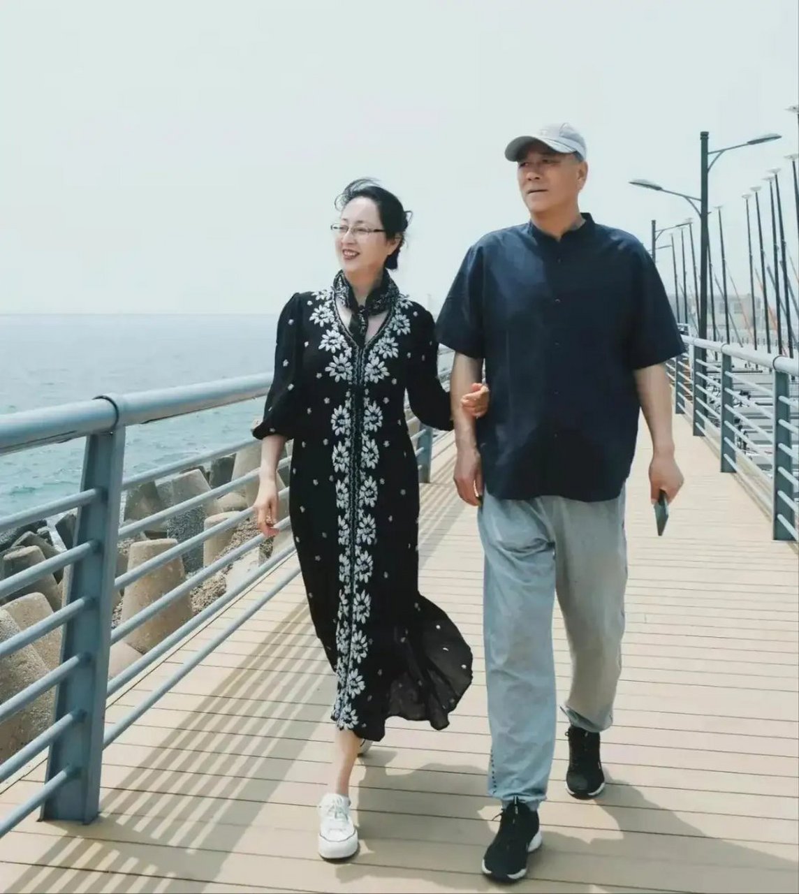 这张照片拍摄于2024年5月,辽宁省大连市海边,一对退休夫妇手挽手游玩